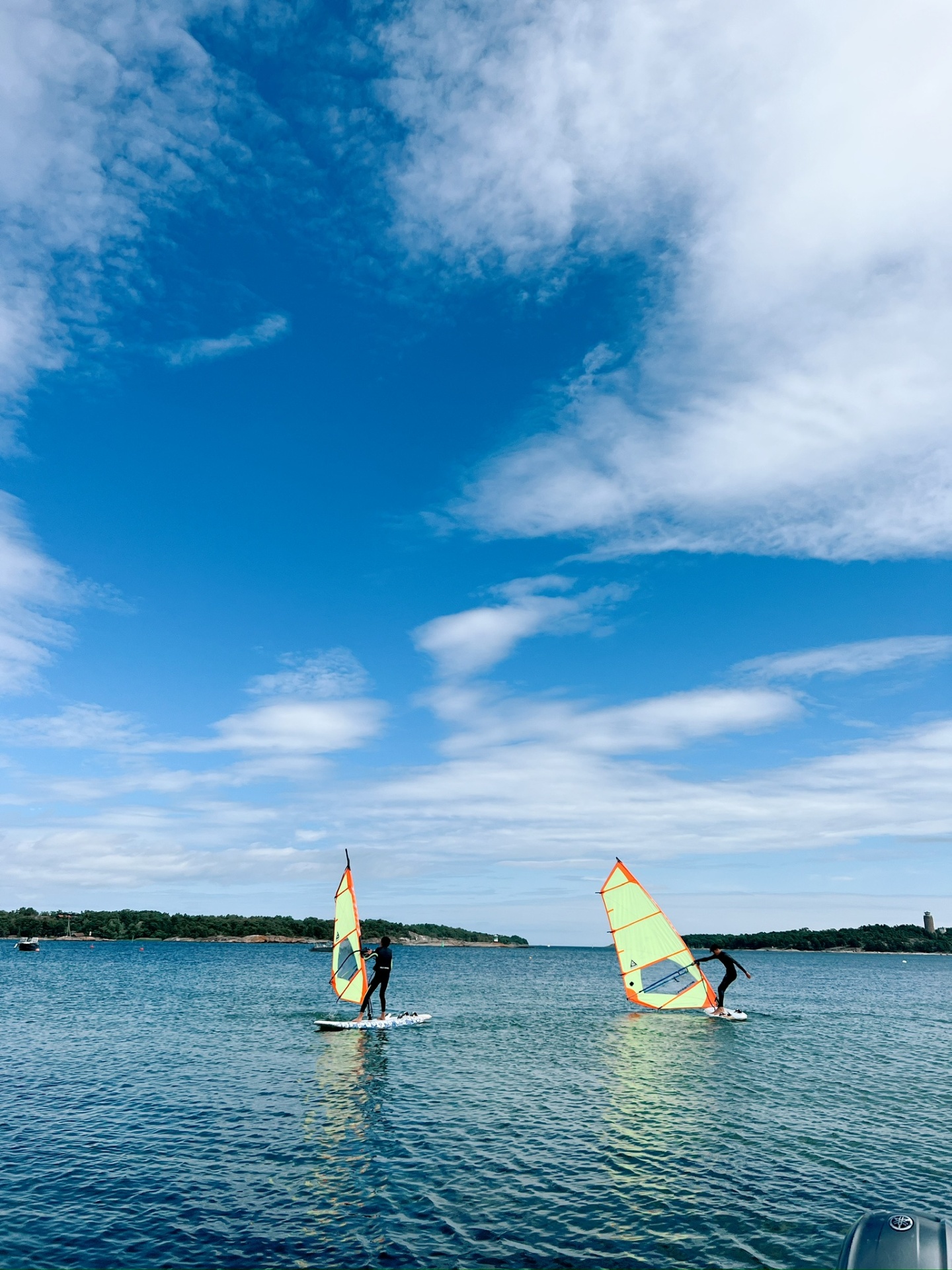 Two windsurfers gliding on calm Sandhamn water under a big sky